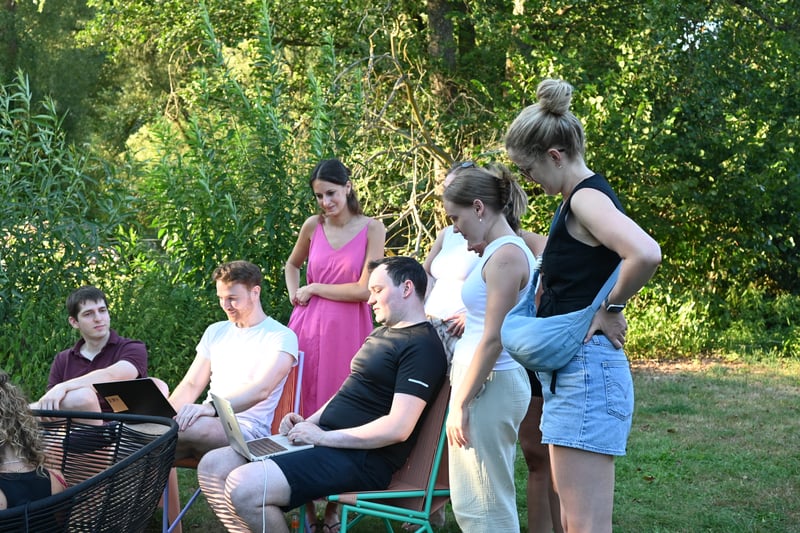 eammitglieder von summ.ai versammeln sich beim Offsite 2026 im Garten und schauen gemeinsam auf einen Laptop.