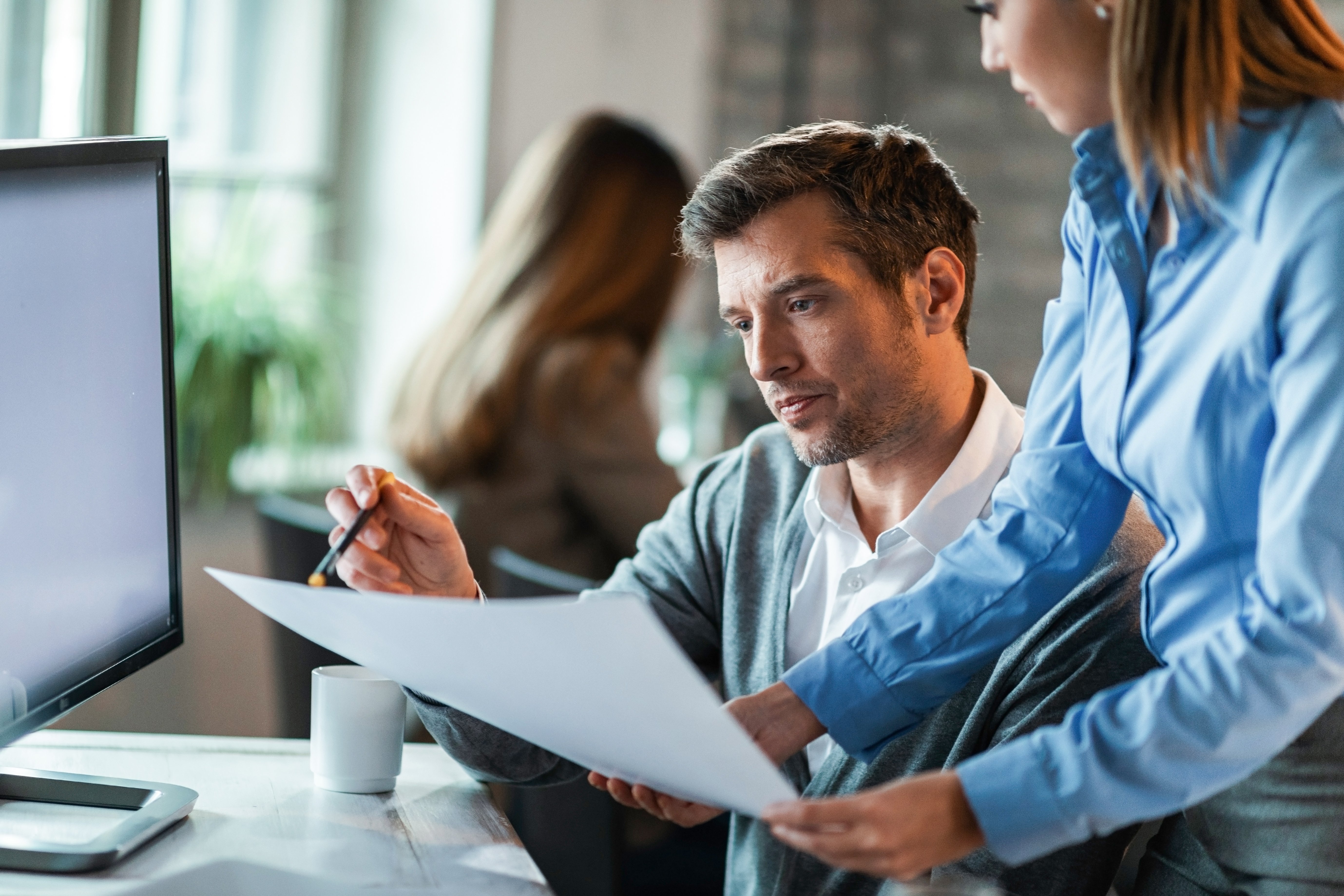 two-business-colleagues-examining-documents-while-working-together-office