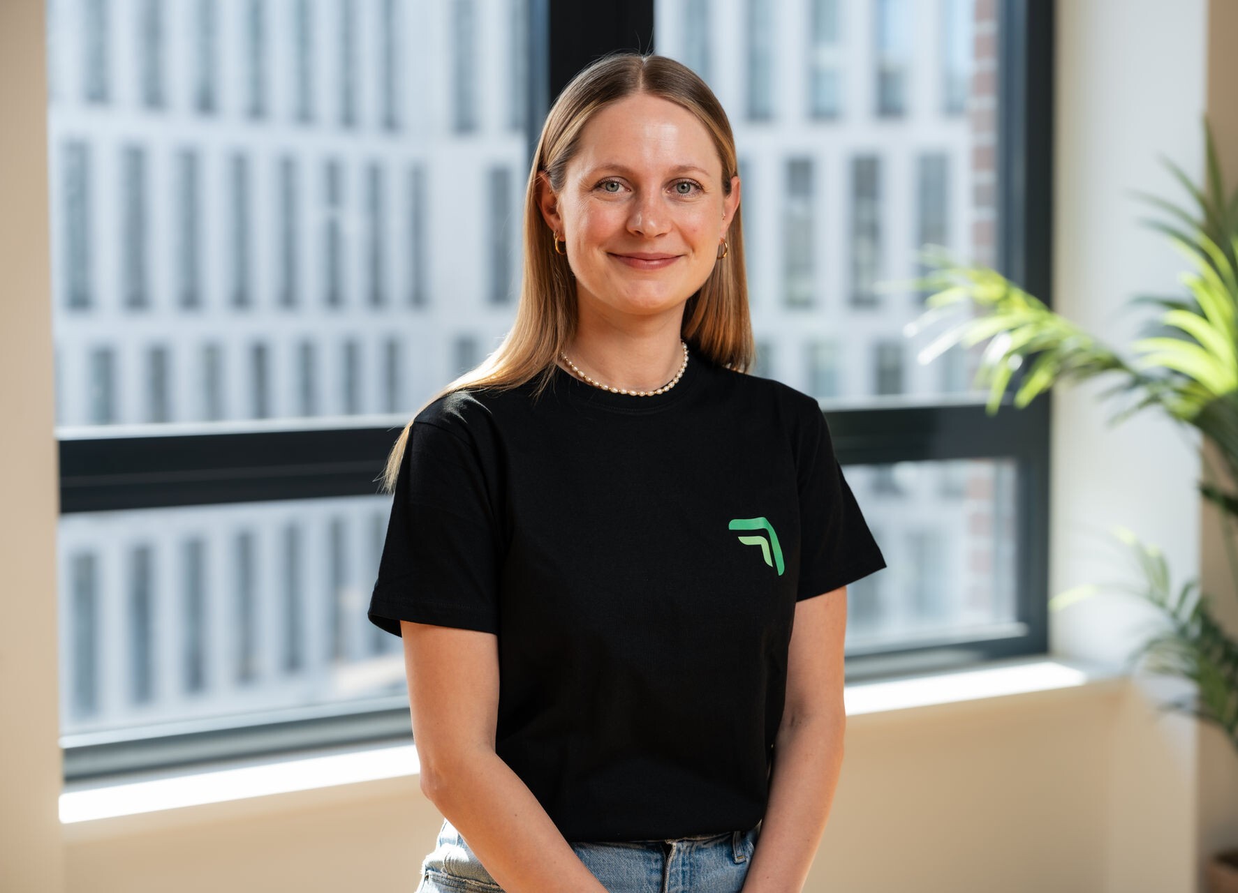 Vanessa König, Gründerin und CRO von summ.ai, sitzt lächelnd vor einem großen Bürofenster.