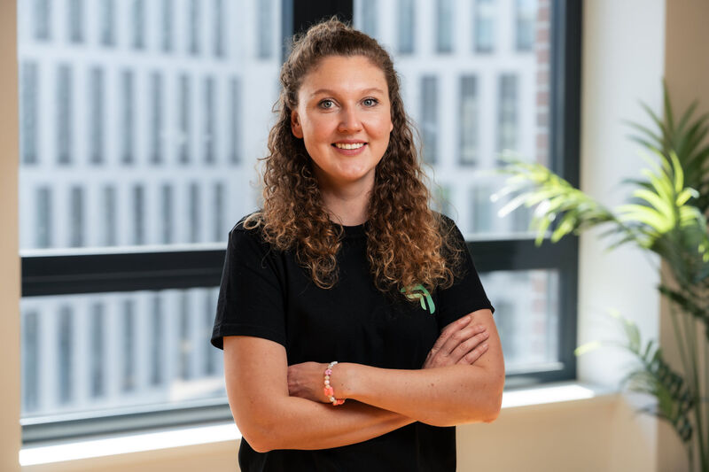 Flora Geske, Gründerin und CEO von summ.ai, steht lächelnd mit verschränkten Armen in einem hellen Büro.