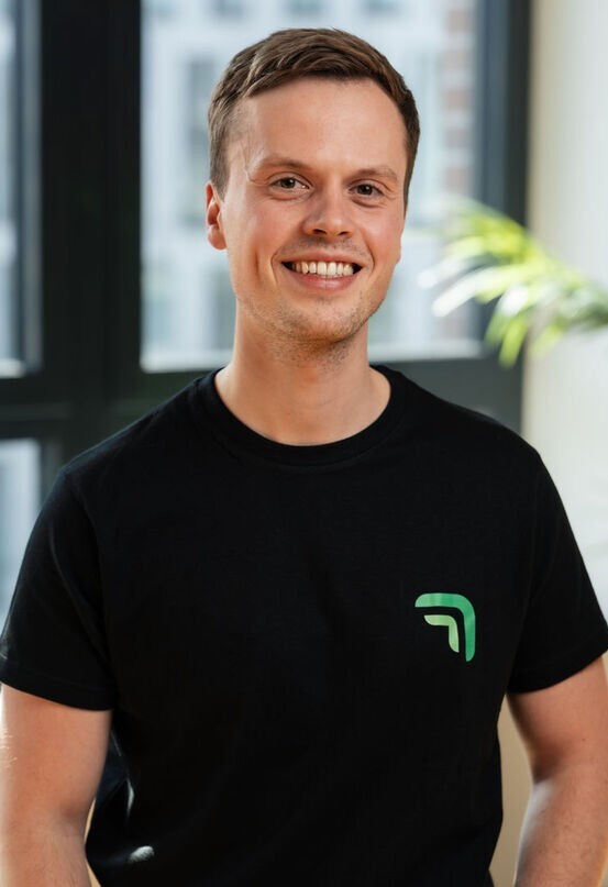 Nicholas Wolf, Gründer und CTO von summ.ai, lächelt in die Kamera in einem hellen Büro.